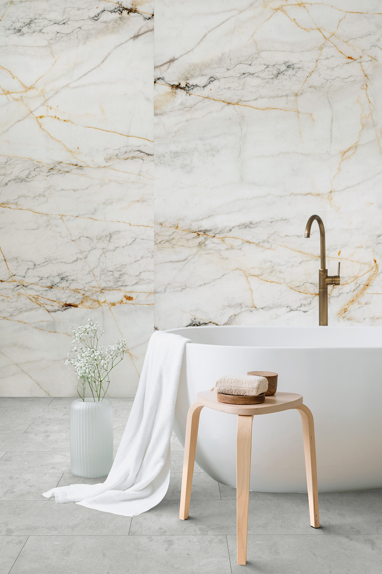 Strukturierte Wandgestaltung mit Marmor-Optik und grauem Bodenbelag in einem Raumdesign mit Badewanne.