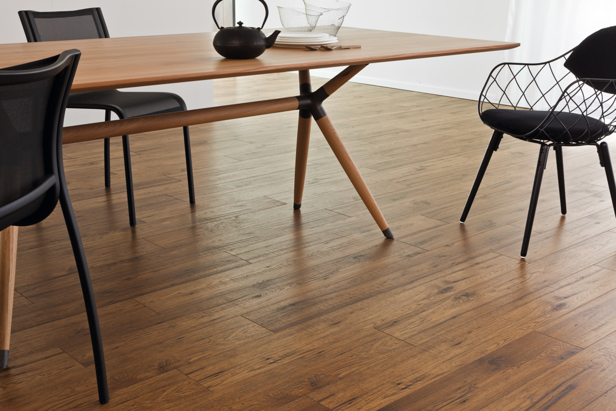 Raumgestaltung mit Holzbodenoptik, Esstisch und schwarzen Stühlen als Interieur-Detail für Bodenbeläge und Wandgestaltung.