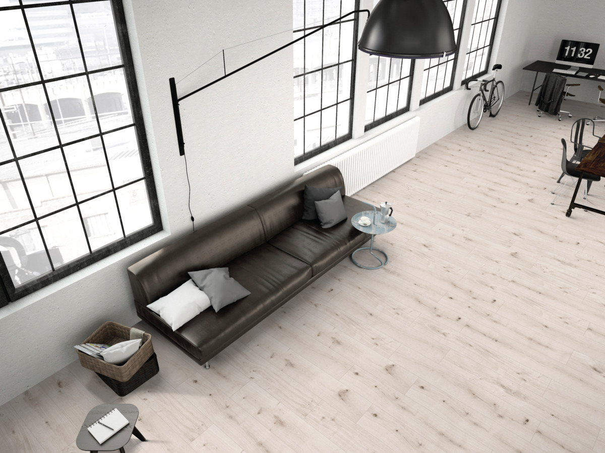 Moderne Raumgestaltung mit hellem Holzoptik Bodenbelag, braunem Ledersofa und industriellen Fenstern.