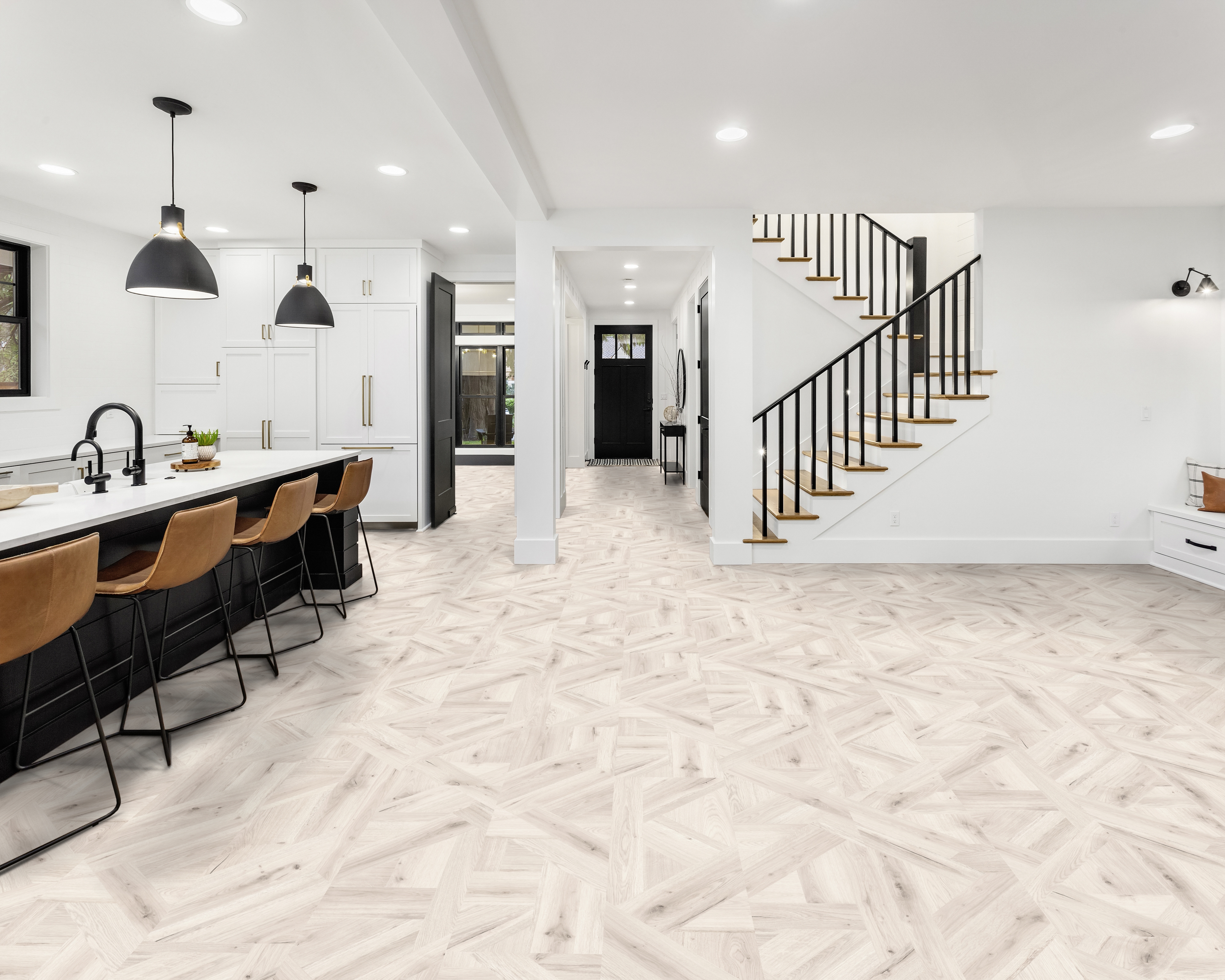 Modernes Interieur mit hellem Holzoptik Boden in geometrischem Muster, weißer Küche und Treppe mit schwarzem Geländer.