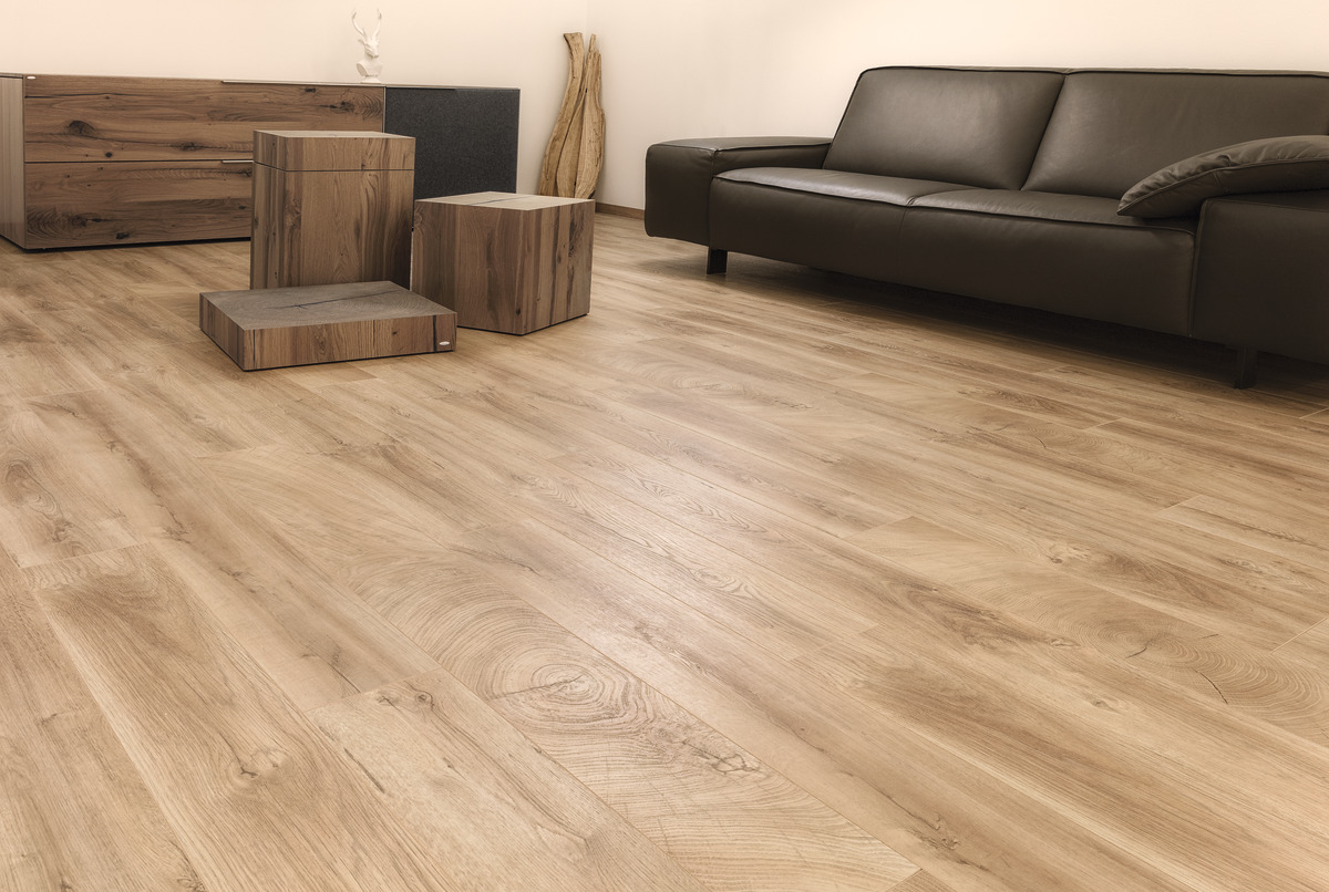 Helle Holzoptik mit lebendiger Maserung als Bodenbelag in einem modernen Wohnambiente mit dunklem Sofa und Holzmöbeln.