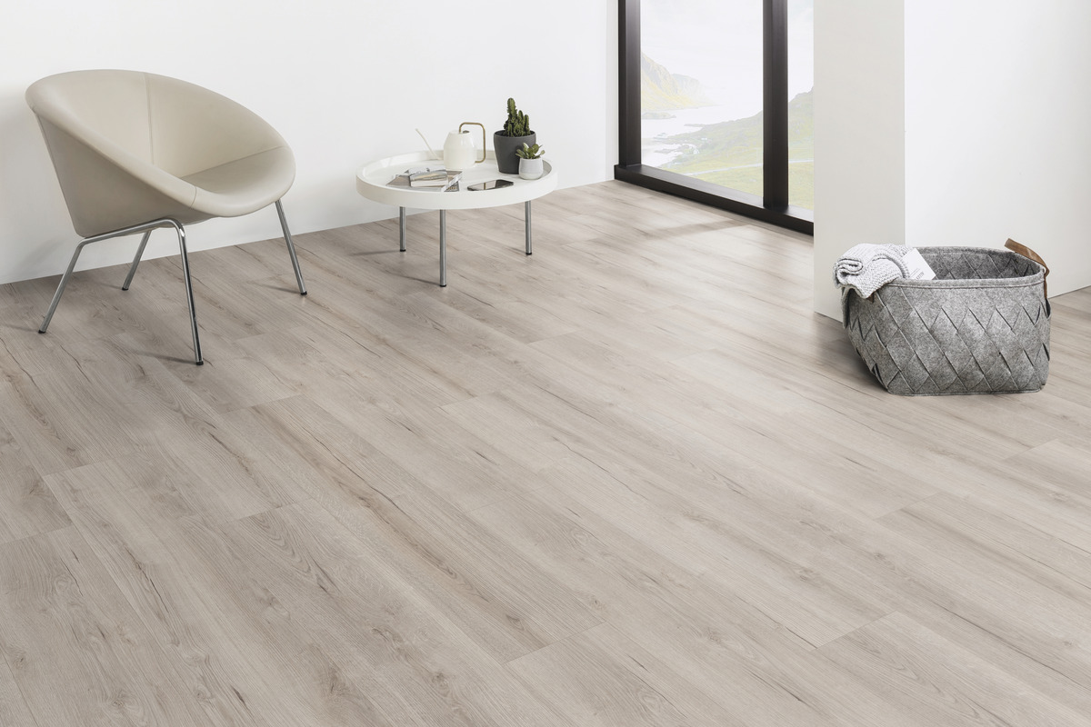 Heller Laminatboden in Eichenholzoptik mit feiner Maserung, verlegt in einem stilvollen Wohnraum mit neutraler Wand und modernen Möbeln.