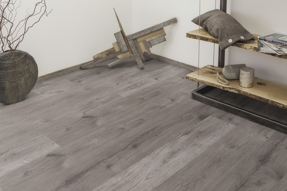 Ein Raum mit grauem Holzboden, weißen Wänden und Einrichtungsgegenständen wie einem Regal und Dekorationsobjekten.
