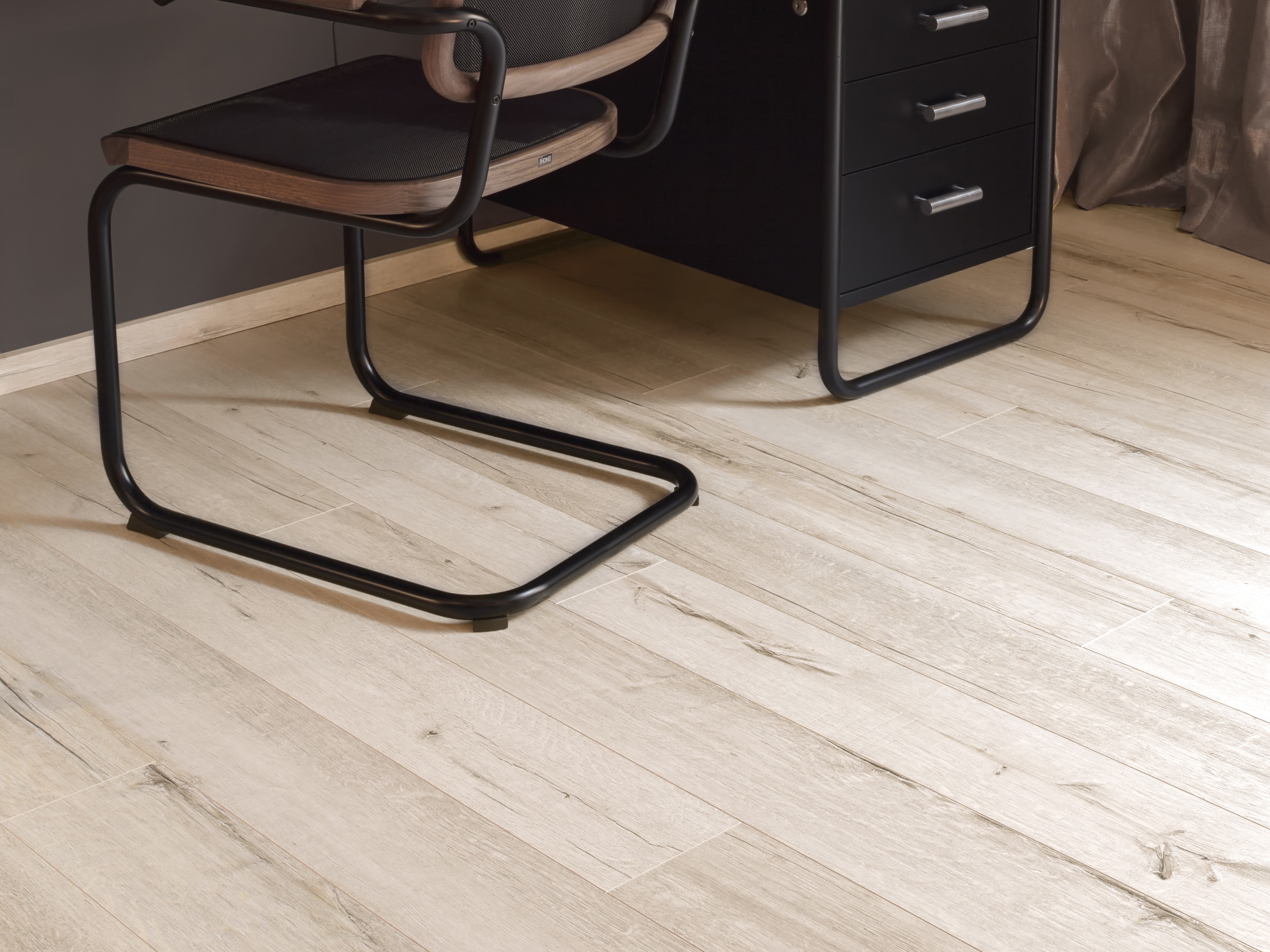 Bodenbelag in heller Holzoptik mit grauer Wand und schwarzem Schreibtisch inklusive Stuhl, Raumgestaltung