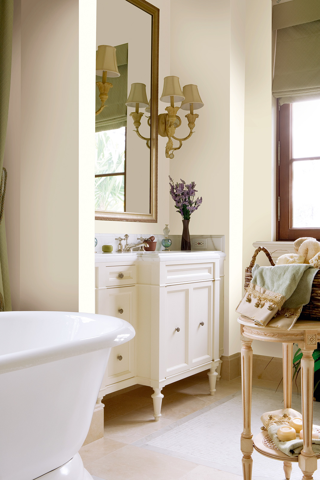 Badezimmer mit freistehender Badewanne, Waschtischunterschrank, Spiegel und Akzentwand im sanften Cremeton. Ein Raumgestaltungsvorschlag.