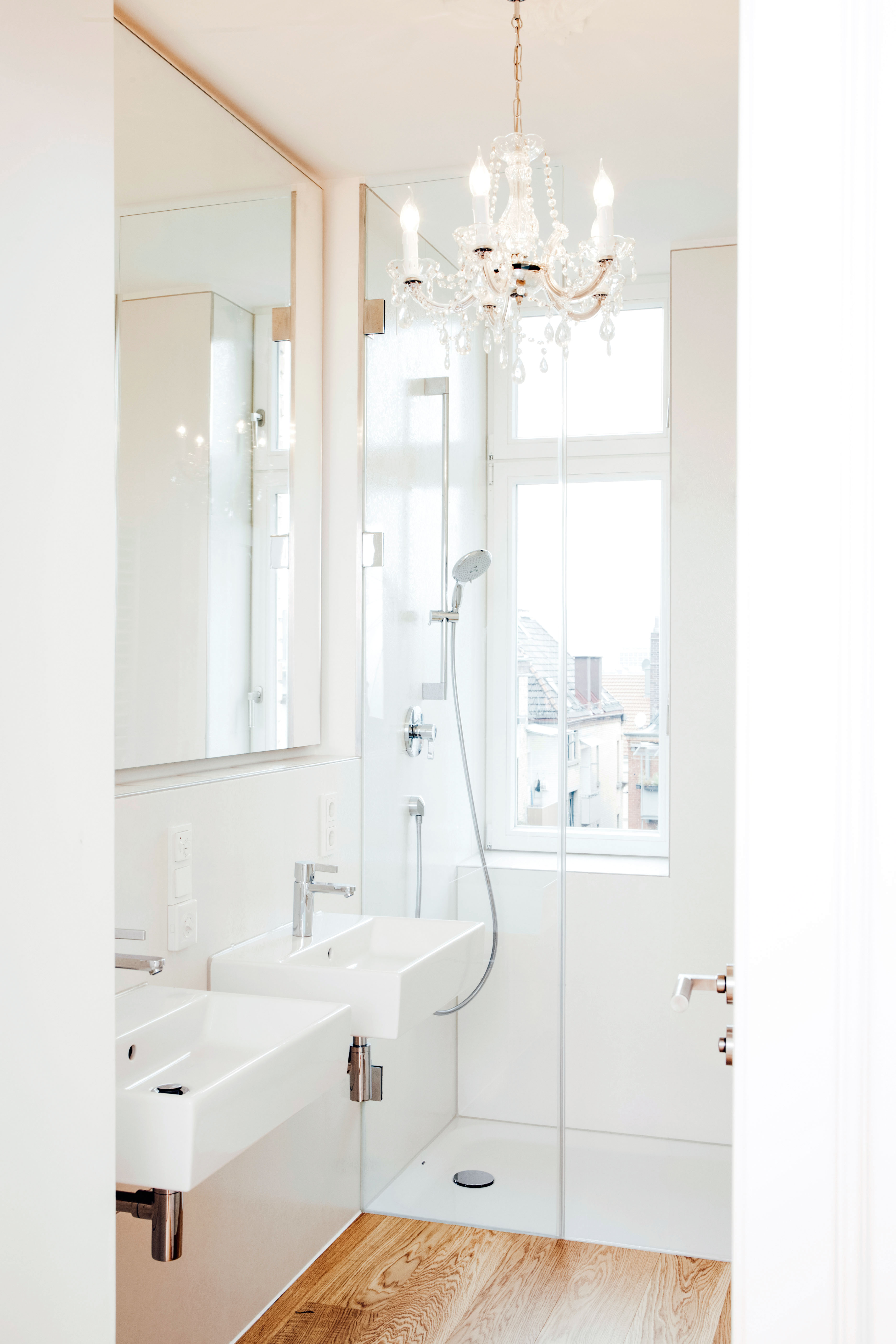 Moderne Badgestaltung mit Dusche und Doppelwaschbecken auf Holzboden und heller Wandgestaltung.