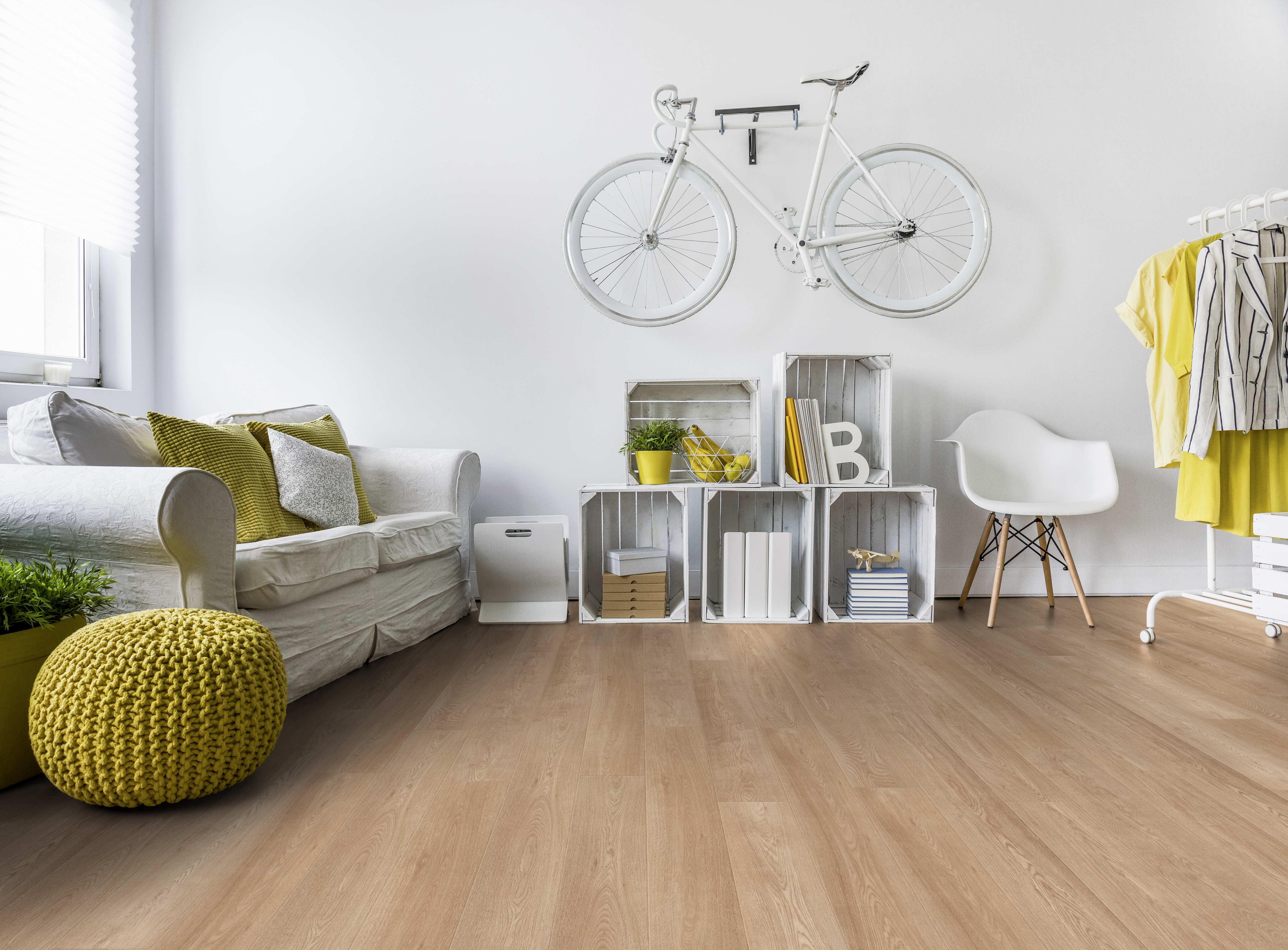 Eine helle Wohnraumgestaltung mit Holzoptik Bodenbelag, weißer Couch, Akzentmöbeln und Wanddekoration.