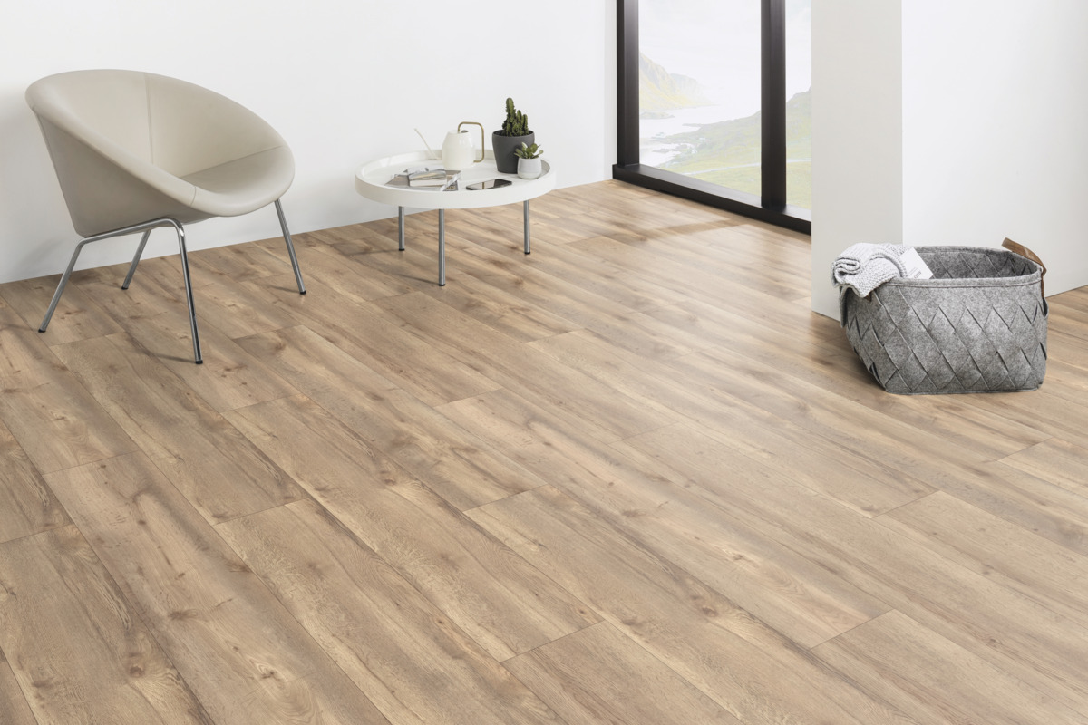 Ein Raum mit hellem Holzboden, weißer Wand und einem Sessel. Ein kleiner Tisch mit Dekoration steht auf dem Boden.