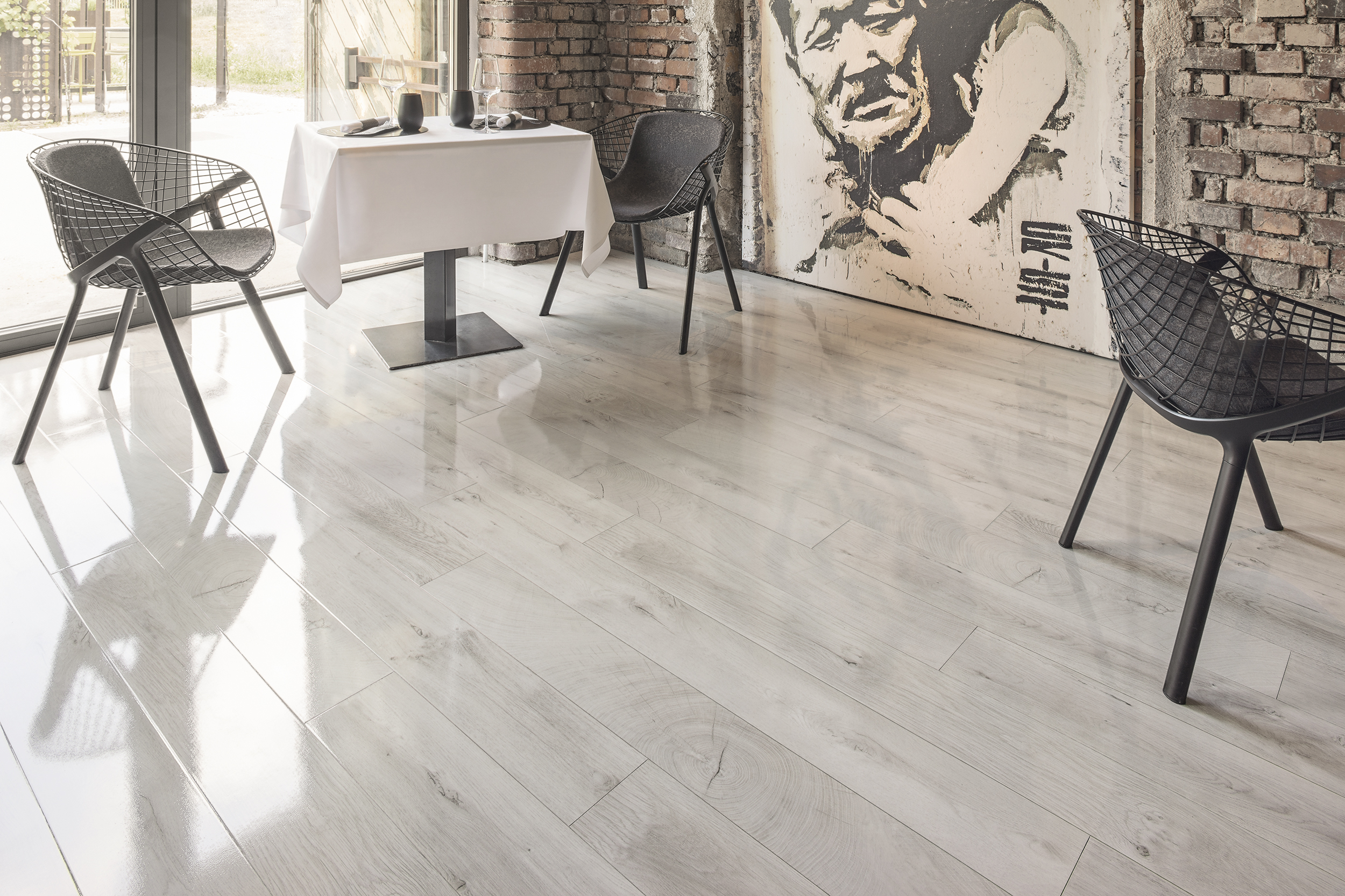 Helle Holzoptik Bodenbelag in einem Raum mit Backsteinwand, Tisch, Stühlen und Wandgemälde für eine moderne Raumgestaltung.