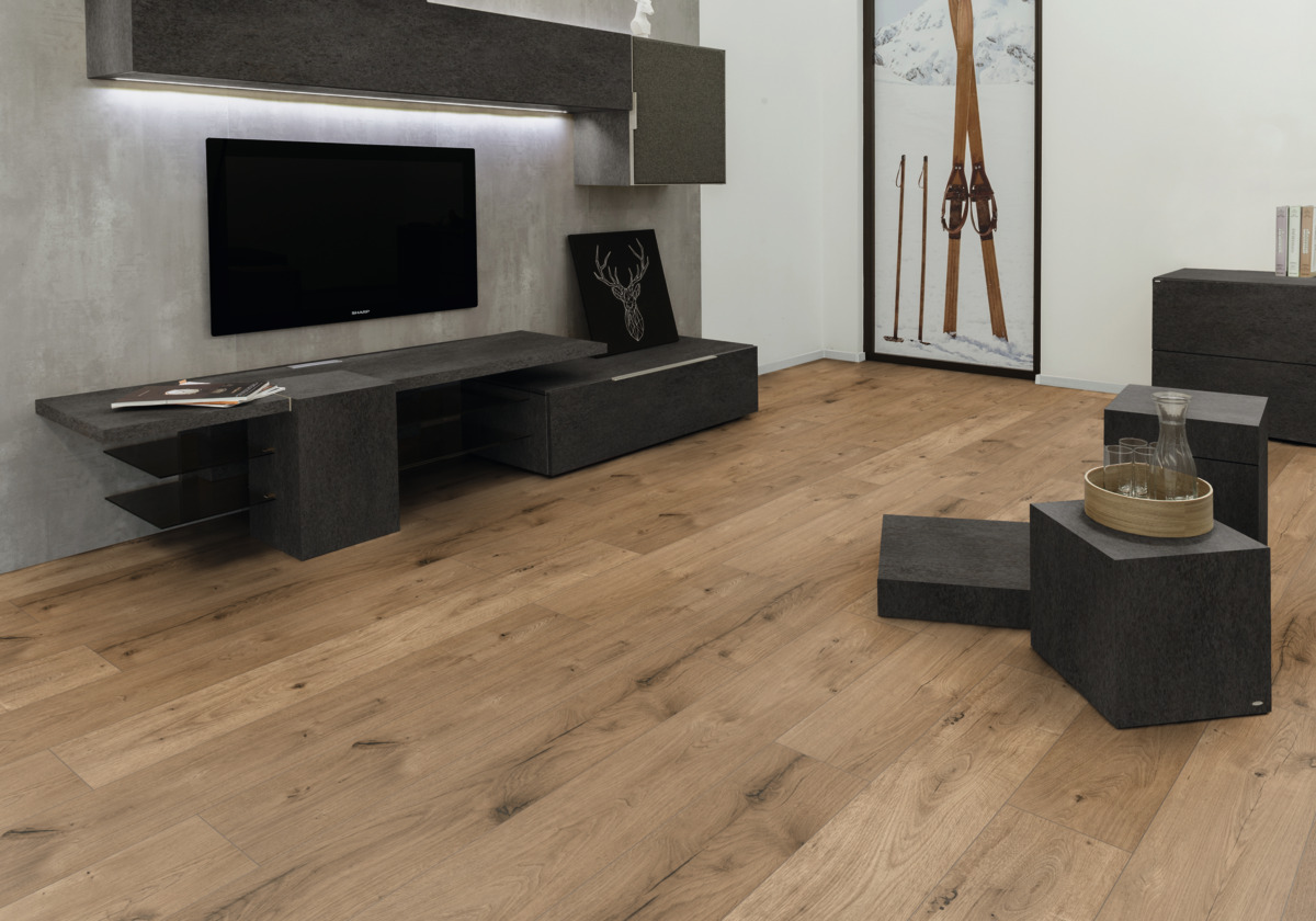 Moderne Raumgestaltung mit Holzboden, Akzentwand und grauem Mobiliar, die Wandgestaltung ergänzt das Interieur.