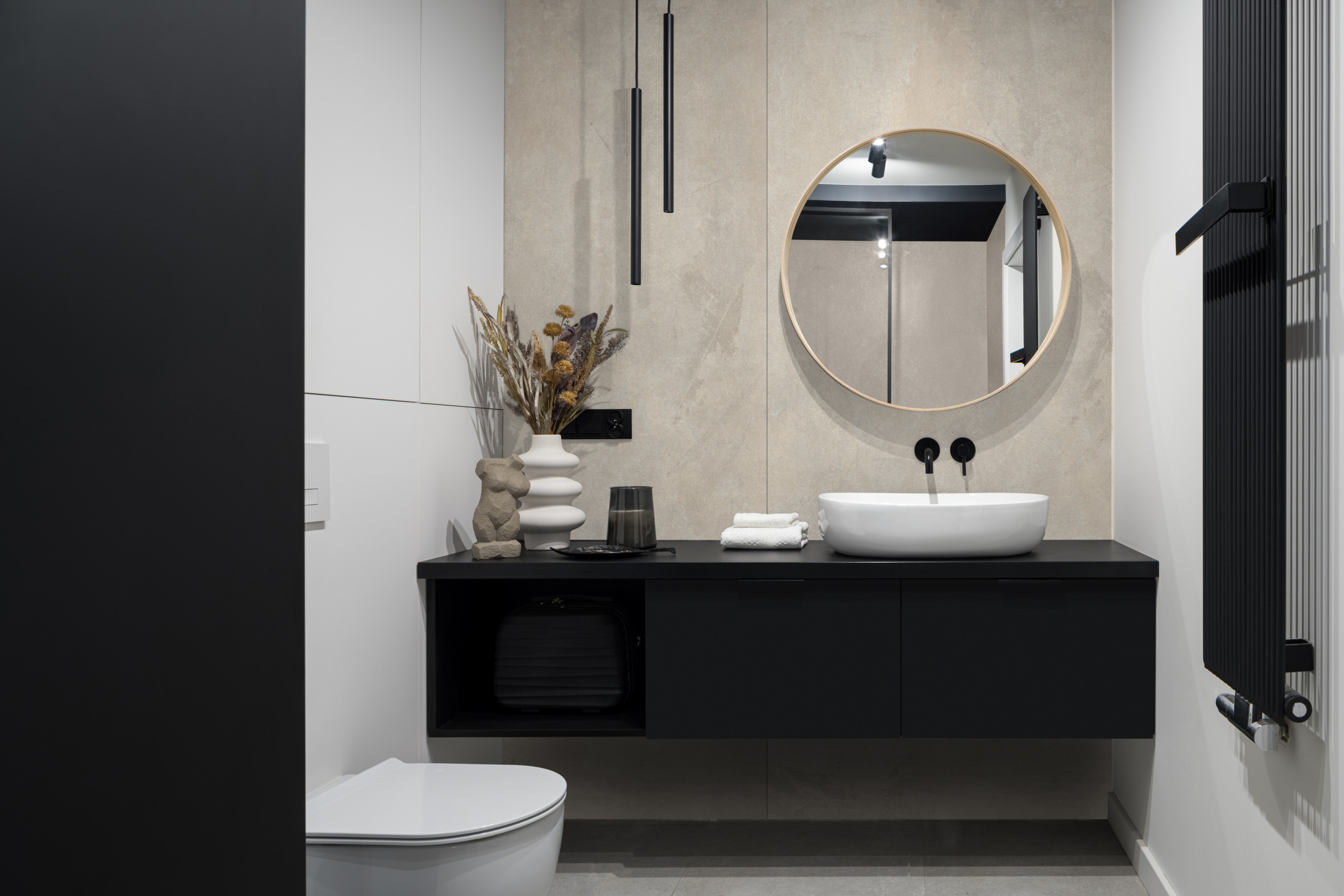 Badezimmer, Waschtisch, runder Spiegel, schwarze Schränke, weiche Fläche